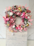 Blush pink and gold frosted Christmas wreath with pink foliage, glittery flowers and pink, white and gold baubles