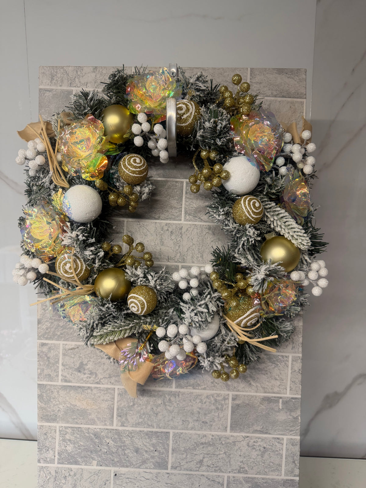 Gold and white frosted Christmas wreath with gold and white baubles, shimmering rose-style decorations and white berries