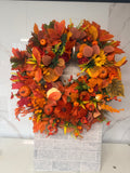 Round autumn wreath with rust and orange foliage, pumpkin accents, burgundy roses and orange berries