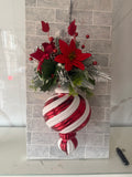 Red and white striped Christmas hanging ornament with artificial red flowers, berries and silver-toned foliage