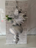 Silver Christmas hanging arrangement with a sequinned mesh flower, frosted greenery, white berries and silver spiral-ridged ornament