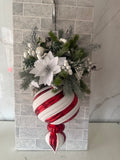 White poinsettia-style Christmas hanging arrangement with frosted greenery, white berries and a red-and-white striped ornament