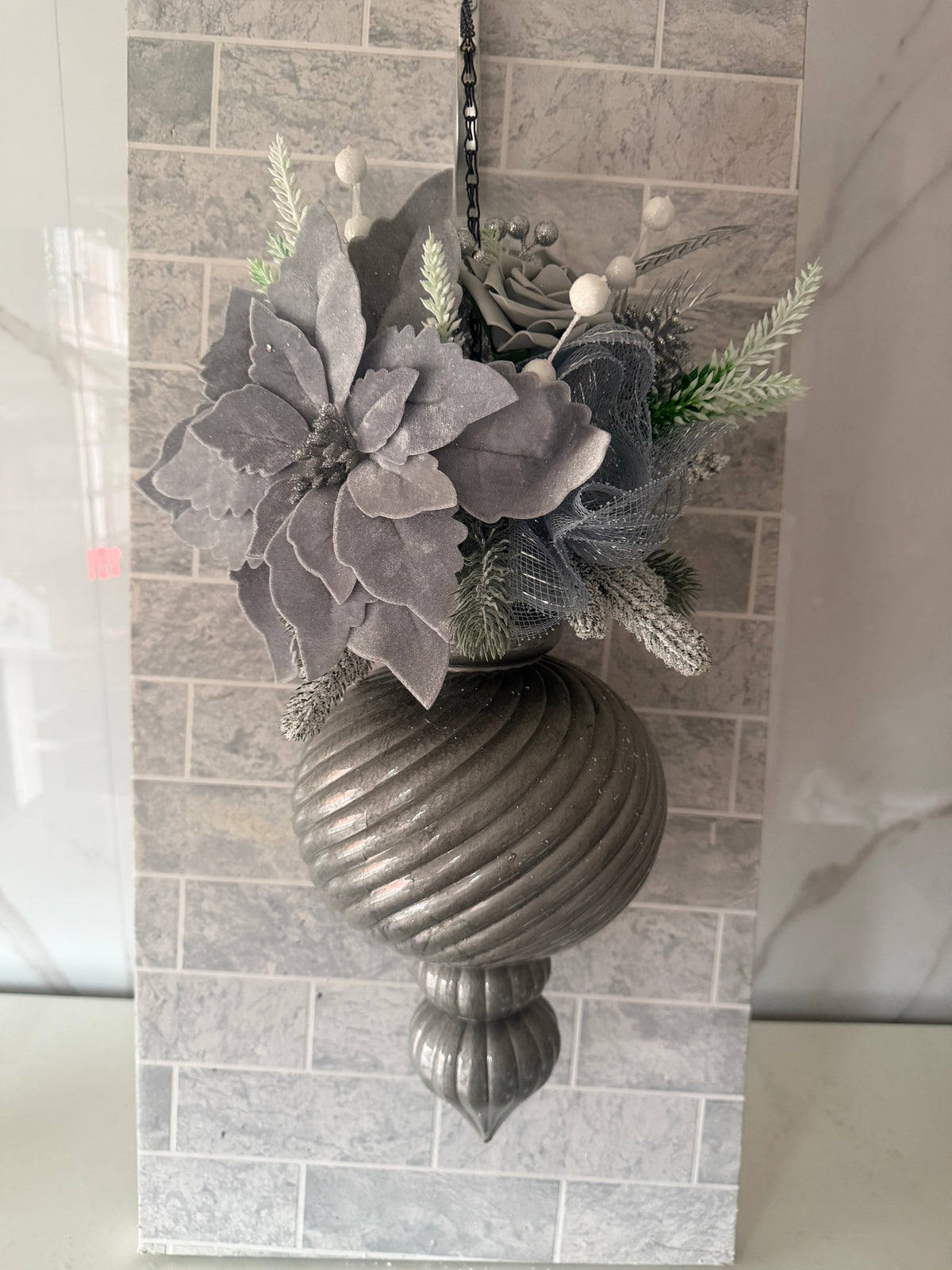Silver and grey Christmas hanging arrangement with grey flowers, frosted greenery, white berries and a silver-toned spiral ornament