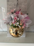 Blush pink and gold Christmas hanging arrangement with pink and cream flowers, white mesh ribbon, frosted greenery and a glossy gold bauble