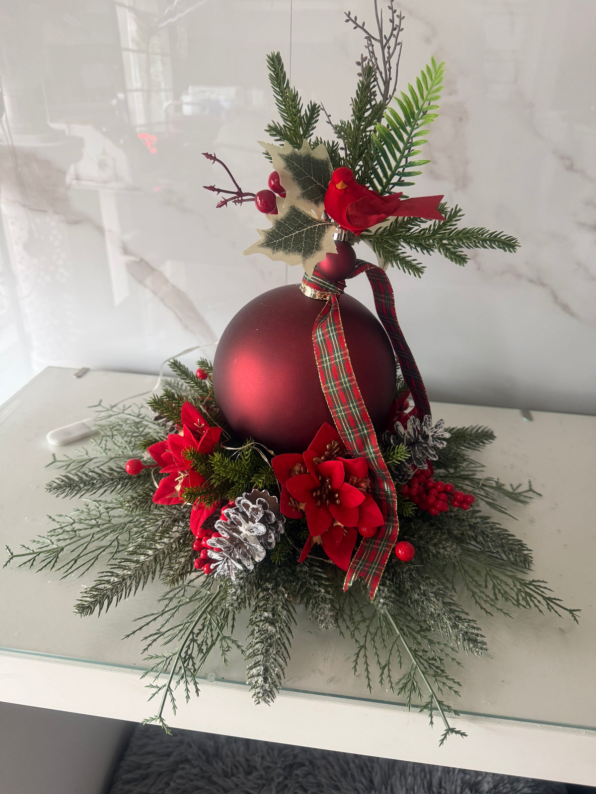 Red bauble Christmas wood slice centrepiece with red bird, red flowers, frosted pine cones and tartan ribbon