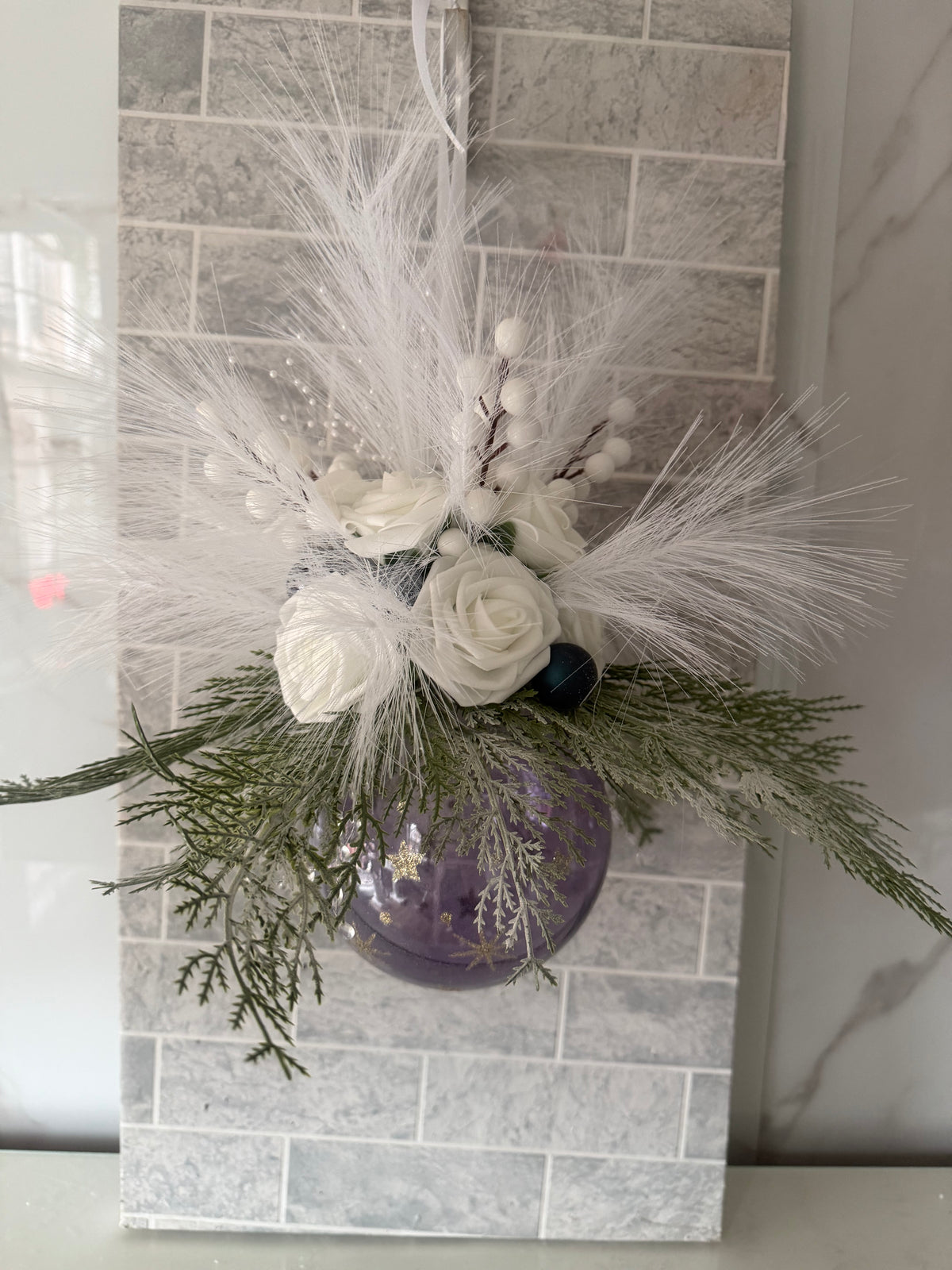 Small purple Christmas bauble hanging arrangement with white roses, white berries and frosted greenery