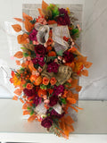 Autumn garland with burgundy and orange flowers, orange leaves, pumpkins and rustic mesh ribbon