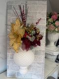 White ribbed hanging Christmas bauble with gold poinsettia-style flowers, burgundy blooms and festive greenery