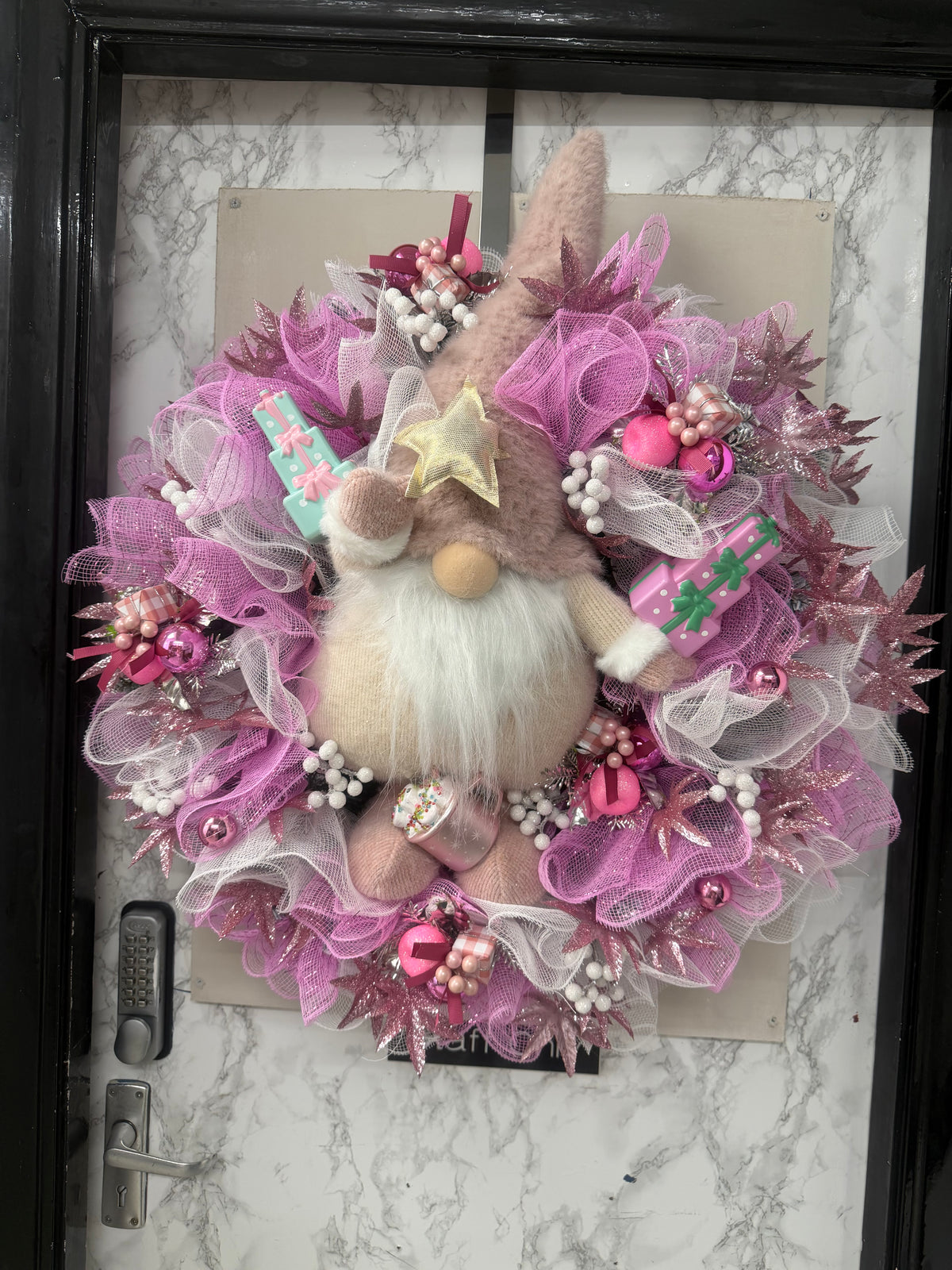 Pink Christmas wreath with plush gnome, white beard, pink mesh ribbon and pastel gift decorations on a door