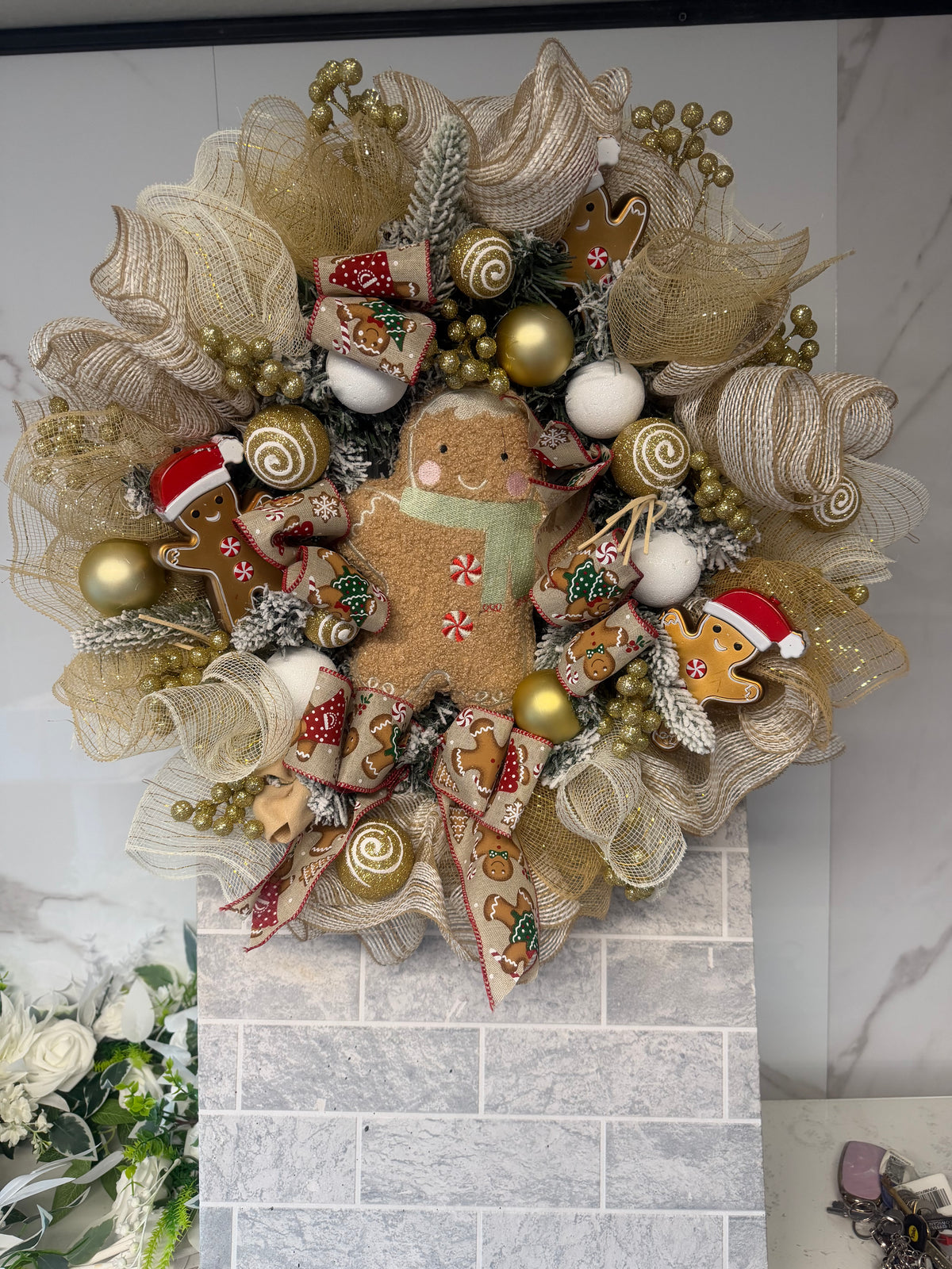 Full view of gold and gingerbread Christmas wreath with gold mesh, patterned ribbon and white baubles